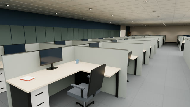 A furnished cubicle with an L-shaped desk, monitor, task chair and file pedestal in a long bank of workstations beside a felt-panelled accent wall